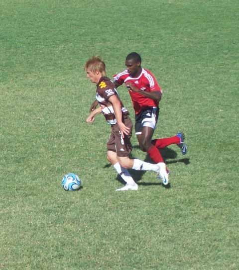From right: Atlentico Platense midfielder Braian Robert being marked by T&T's Clyde Leon.